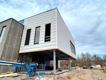 Upward angled view of a cantilevered view at Paragon Star withwhite rigid insulation panels, GreenGirt Max CMH Z-girts, with a boom lift positioned below