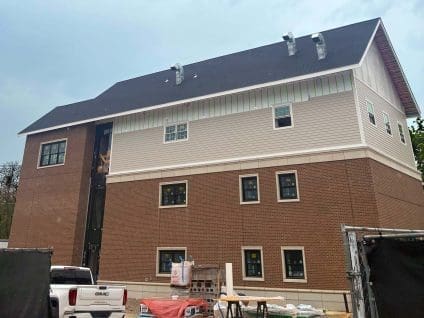 Multi-story building nearing completion with SMARTci building enclosure system beneath lap siding and brick veneer.