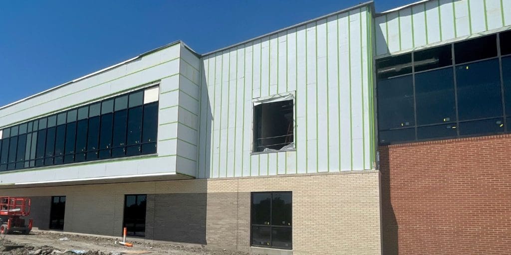 Vertical and horizontal GreenGirt Max CMH Z-girts, part of the SMARTci building enclosure system, with insulation on the upper wall of a commercial building above brick veneer.
