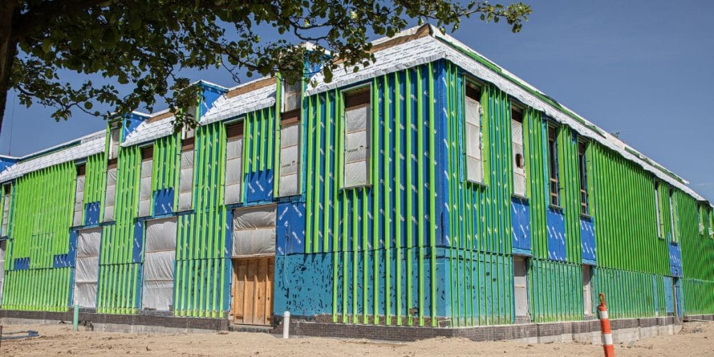 GreenGirt XO thermal window framing installed at Oakland Community College, with green and blue Z-girts running across the wall over a weather-resistive barrier.