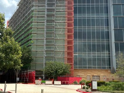 Independent Financial Headquarters, distant view of the scaffolded tower behind a landscaped driveway and low concrete wall
